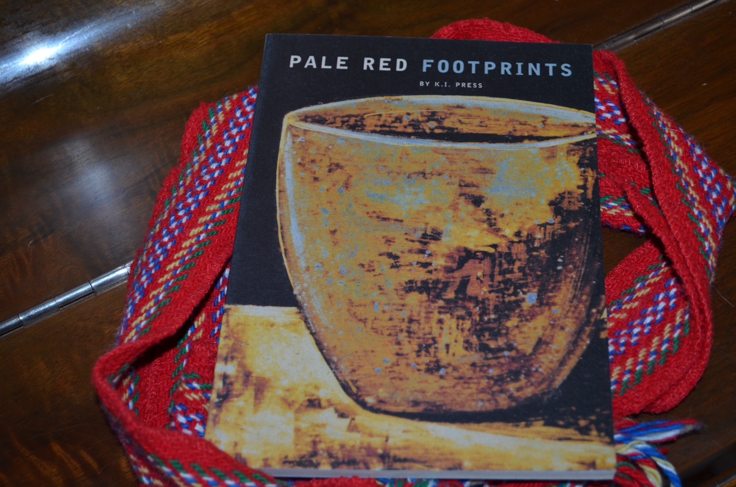 Book Pale Red Footprints surround by a red sash.